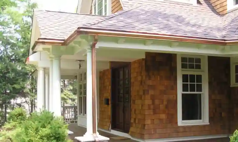 Copper gutters and downspout on a cedar shingle home with a covered porch