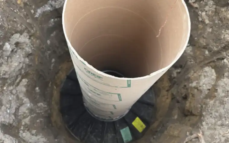 Concrete footing form tube with a spread footing base in the ground