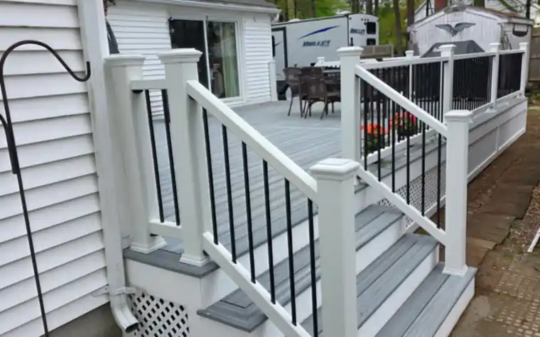 Deck stairs with gray composite treads and white railing with black balusters