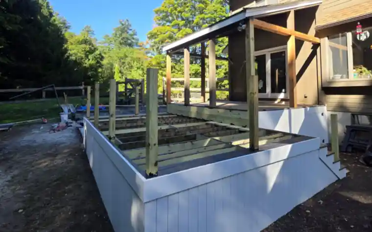 Raised deck framing with white PVC skirting next to a covered porch